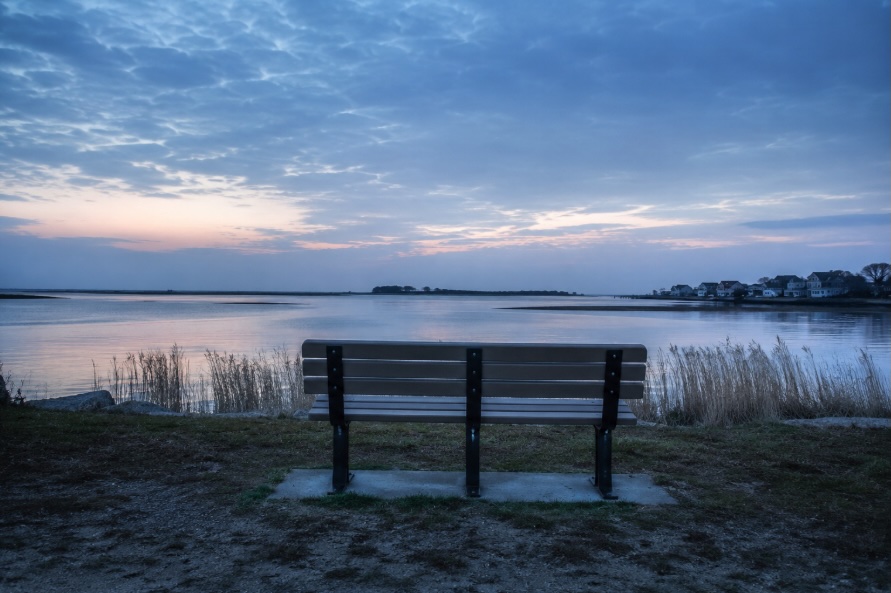 Empty park bench overlooking a calm bay on the New Jersey Shore at dawn